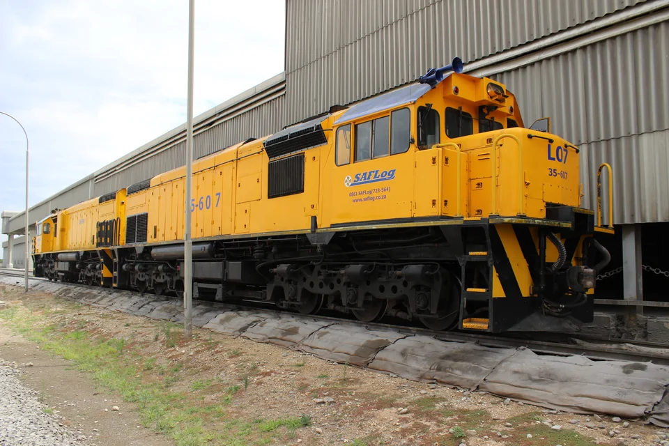A yellow locomotive beside a corrugated metal building.
