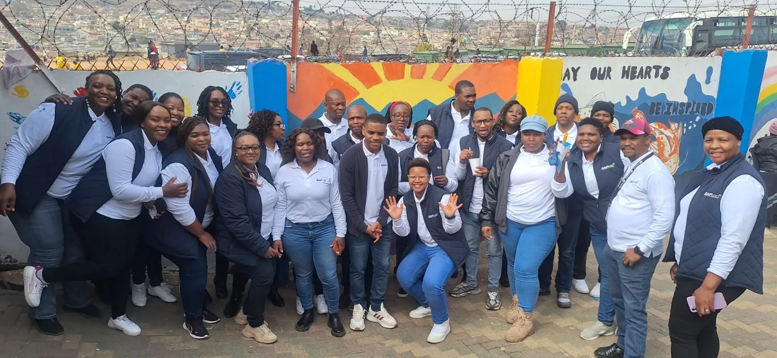 Volunteers posing together in front of a colourful wall mural.