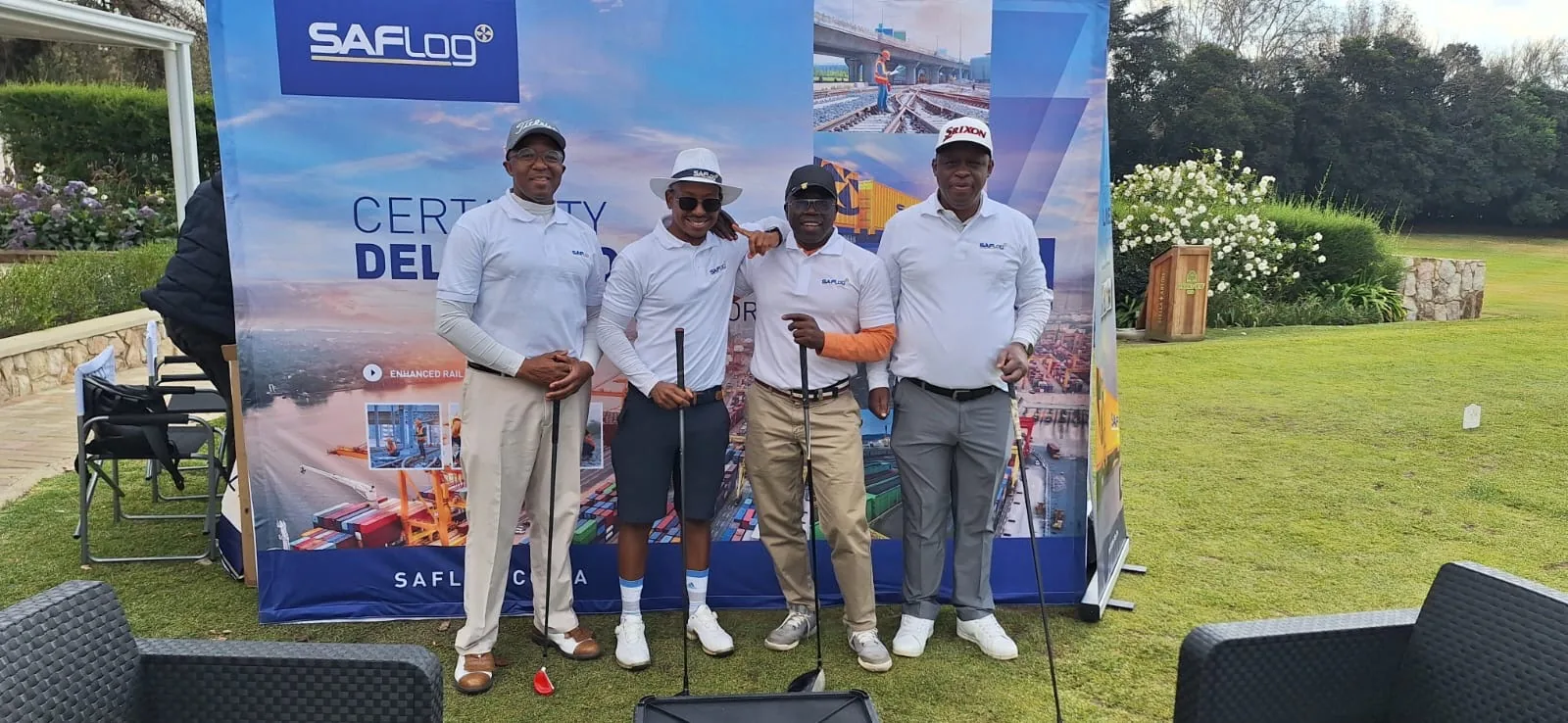 Four golfers standing beside a SAFLog banner on a golf course.
