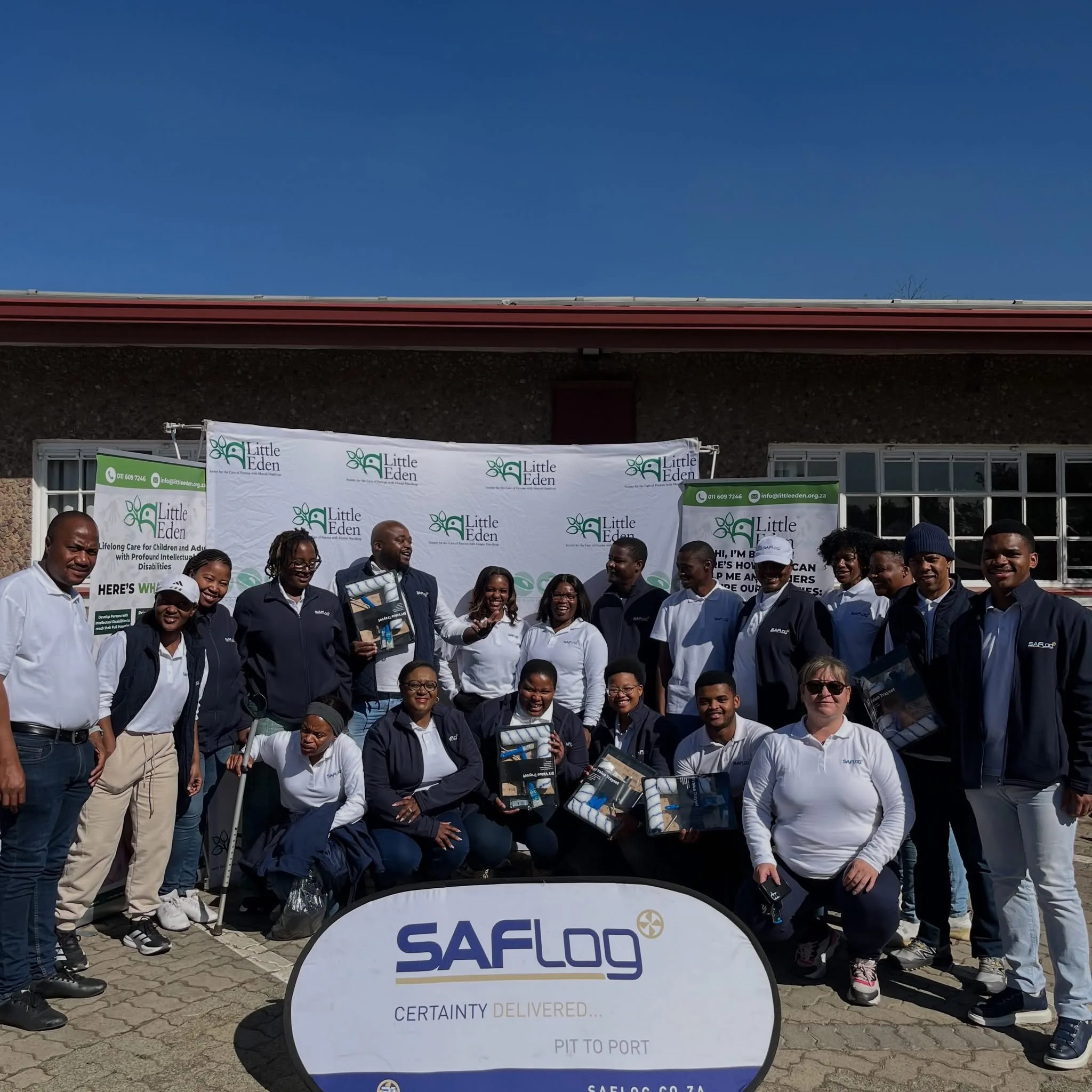A group posing outside a building with a SAFLog sign.