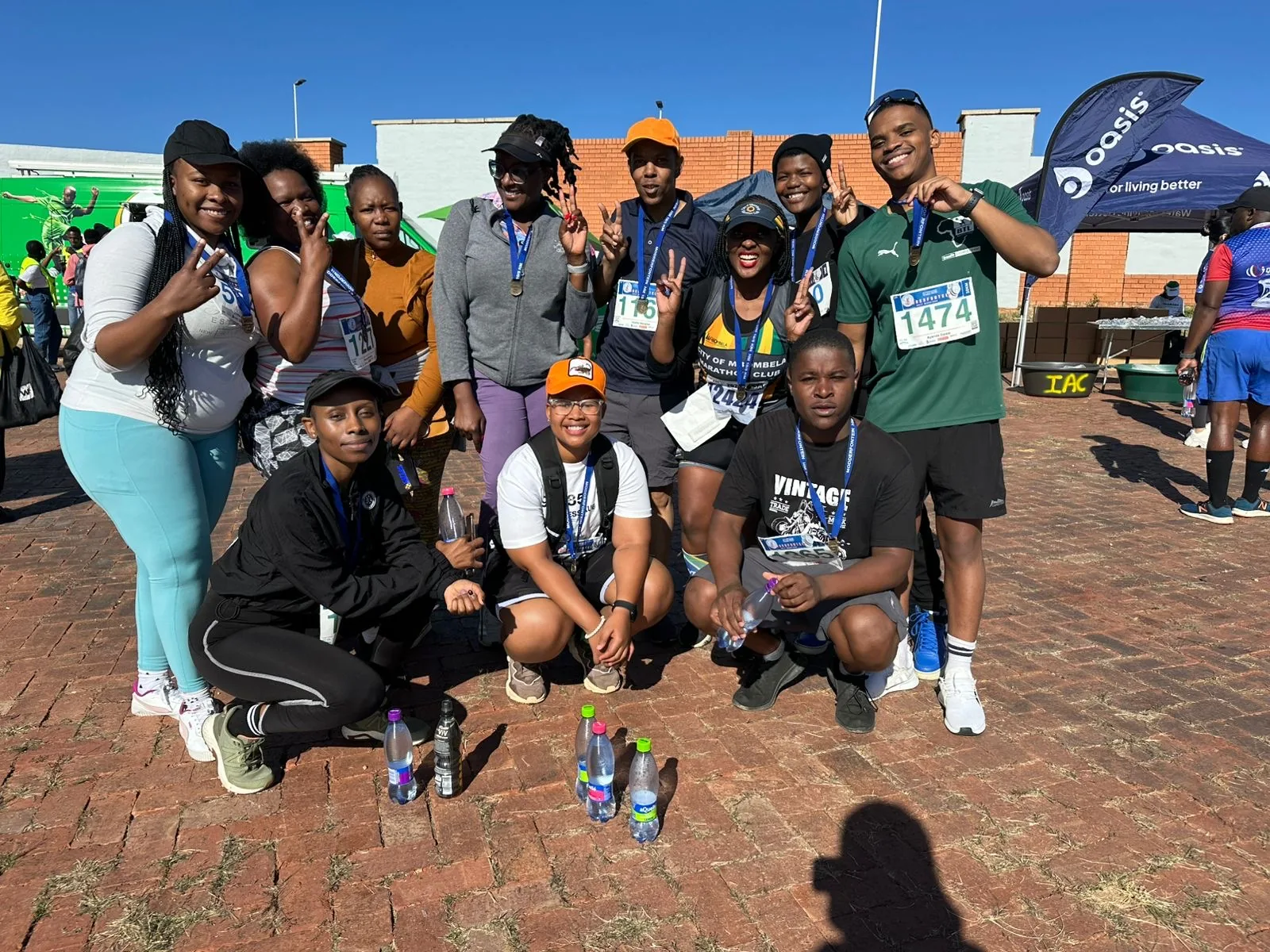 A group of runners posing together beside event banners outdoors.