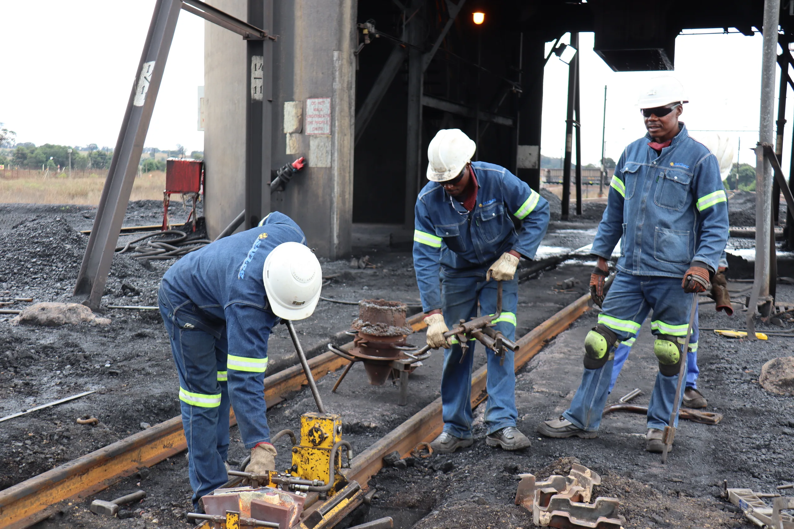 Rail workers operating equipment on a railway track.